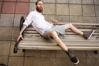 Bankta yatan havalı sakallı hippi. Biçim ve moda