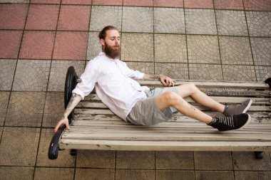 Dövmeli hippi bankta yatıyor. Biçim ve moda