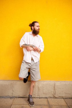 Dövmeli sakallı çekici adam sarı duvar açık poz üzerinde