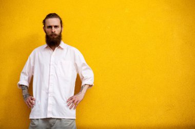 Sarı duvardaki sakallı hippi dövmesi dışarıda poz veriyor.