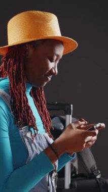 Dikey video: Uygulamada video oyunu oynayan gülümseyen yetişkin, tatil gezisinde internet oyunları ile ilgili bir sorun yaşıyor. Genç bayan gezgin oyun oynamak için online yarışmadan zevk alıyor.