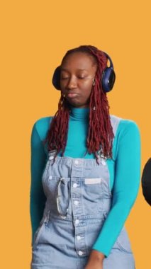 Dikey video: Neşeli yetişkin müzik dinliyor ve müzik kulaklıkları kullanıyor, tramvay çantaları ve bavulları kamerada. Genç gezgin dans hareketleri sergiliyor ve kulaklıkla mp3 şarkılarının tadını çıkarıyor..