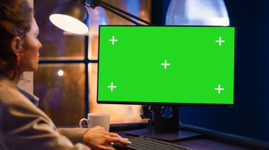 Genç girişimci ekrandaki yeşil ekran görüntüsüne bakıyor, bilgisayarı krom boş şablonla kontrol ediyor. Açılış yöneticisi izole edilmiş telif alanı ekranı ile çalışma saatleri dışında çalışıyor.