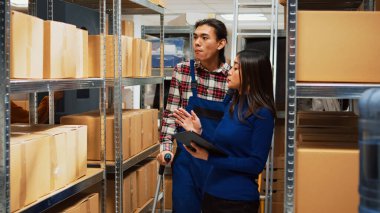 Tabletteki lojistiği analiz eden, dağıtım yönetimi ve gelişimi hakkında konuşan erkek çalışan. Koltuk değnekli genç adam girişimciyle çalışıyor..