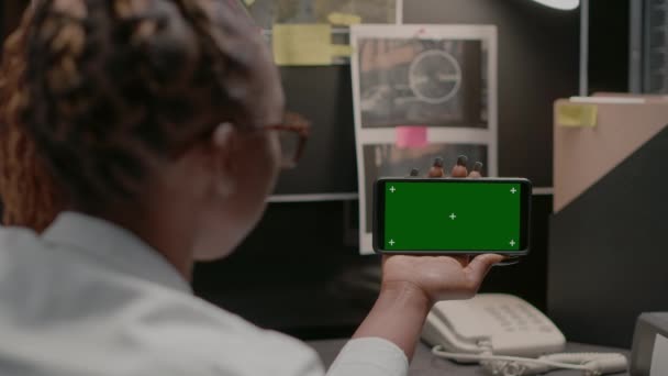 警务人员在证物室使用绿色屏风 展示模拟展示及进行刑事调查 检查员用智能手机检查孤立的色键模板 — 图库视频影像