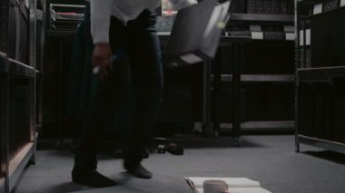 Katta oturan kadın dedektif raporları ve güvenlik görüntülerini kontrol ediyor, şüpheliyi yakalamak için dava bilgilerini inceliyor. Kanun adamı sabıka kayıtlarını inceliyor, sabıka kayıtlarını kontrol ediyor..