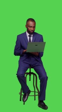 Dikey video: Şirketin internet sitesinde arama yapan, sandalyede oturan ve stüdyoda dizüstü bilgisayar kullanan çalışanlarının ön görüntüsü. Kablosuz bilgisayar üzerinde internet ağı sayfası ile çalışan yetişkin girişimci