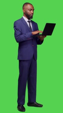 Dikey video: Güvenilir yöneticinin interneti taramak için dizüstü bilgisayarı kullanmasının yan görüntüsü, tam vücut yeşil ekran arkaplanı üzerinden çevrimiçi web sayfasına bakıyor. Taşınabilir bilgisayarla çalışan erkek girişimci