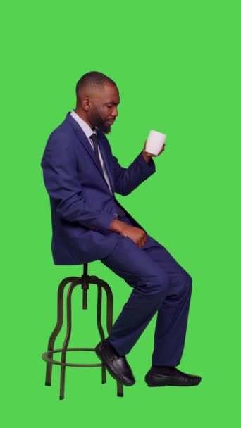 사업가가 의자에 커피를 스크린으로 스튜디오에 모습입니다 카메라에서 카페인 음료를 마시는 — 비디오