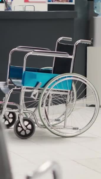 垂直ビデオ 医療機関の車椅子付きの空のフロントデスクロビー 障害者フレンドリーなセンターでの座席とヘルスケアチラシでいっぱいの病院のレセプションエリア 身体障害回復 — ストック動画