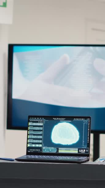 垂直视频 笔记本电脑在办公桌上运行脑部诊断 医院登记柜台用于显示医疗保健的神经系统 医疗中心候诊室屏风神经学扫描分析 — 图库视频影像