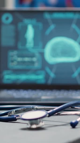 垂直ビデオ 医療施設のロビーで脳X線スキャンで空のカウンター 神経科学分析を示す登録フロントデスクに置かれたラップトップ 画面上の神経系診断 手持ち撮影 — ストック動画