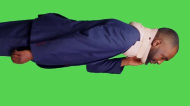 Dikey video: Servikal yaka köpüğü kullanarak ağrıyı dindirmek için kırılan genç yetişkinlerin profili, tıbbi nedenlerden ötürü omurga yaralanmaları. Takım elbiseli bir ofis çalışanı yeşil ekranda boyunluk takıyor.
