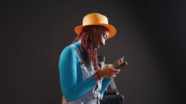 Neşeli gezgin stüdyoda online alışveriş yapıyor, cep telefonu uygulaması üzerinden ödeme yapmak için kredi kartı kullanıyor. İnternet sitesinden bagaj alan genç bir kadın, akıllı telefon alımı. El kamerasıyla..