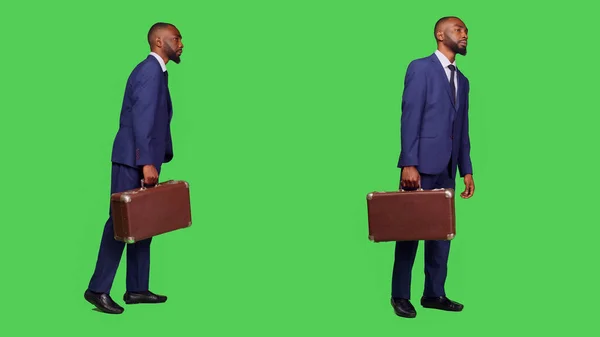 会社の職場でスーツケースを持っている若いマネージャーは フルボディの緑の画面を背景にスタジオに立っている ビジネススーツを着て カメラにブリーフケースの荷物を運ぶスタートアップ労働者 — ストック写真