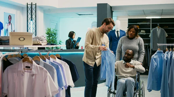 有身体残疾的年轻人在商店里检查衣服 在服装店里购买新的系列品牌 轮椅使用者从时尚精品店 商业活动购买正装 — 图库照片