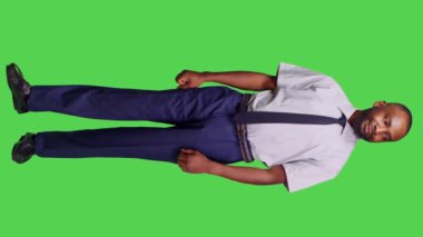 Dikey video: Afrikalı Amerikalı iş adamının tüm yeşil perde arkasında poz verirken ön görüntüsü, kamera önünde resmi bir iş elbisesi giyerken kendini güvende hissediyor. Erkek şirket çalışanı