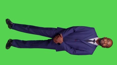 Dikey video: Girişim yöneticisinin kamerada kendini güvende hissetmesinin ön görüntüsü, kurumsal işte çalışmak için takım elbise giymesi. Gülümseyen yetişkin girişimci yeşil ekran tüm vücut arka planı üzerinde poz