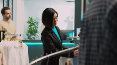 Perakende mağazasında resmi giyinen Asyalı müşteriler gardırobu artırmak için şık markalar kullanıyor. Moda ürünleri alan yetişkin bir kadın, küçük işletme konsepti..