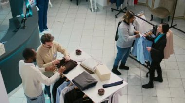 Çeşitli müşteriler butik dükkanından mal alıyor, alışveriş merkezindeki elbise koleksiyonlarını kontrol ediyor. İnsanlar resmi ya da günlük giysiler için alışveriş yapıyorlar, yeni moda markalar..