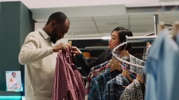 Sklep Asystent Dając Ubrania Człowieka Aby Przymierzyć Butiku Odzieżowym Pomagając — Wideo stockowe