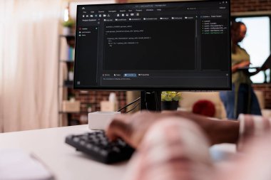 Afrika kökenli Amerikalı programcının, kız arkadaşı bilgisayarında uzaktan kumandayla çalışırken kişisel bilgisayarında klavyeyle kod yazmasına yakın çekim. Bilgisayar üzerinde yazılım geliştirme programında sistem geliştirici.