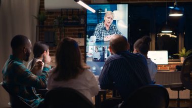 Çalışanlar video konferansında orta yaşlı iş arkadaşını selamlıyor, el sallıyor, iş arkadaşlarıyla görüntülü görüşme yapıyor. Ofis çalışanları, iş kadınlarının konuşmalarını dinlemek, gece telekonferanslarında konuşmak.