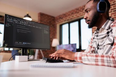 Veritabanı geliştiricisi oturma odasında uzaktan çalışan kişisel bilgisayar kullanarak kablosuz kulaklık programlama algoritması kullanıyor. Afrika kökenli Amerikalı serbest kod yazıcı ve evde hata ayıklama kodu.