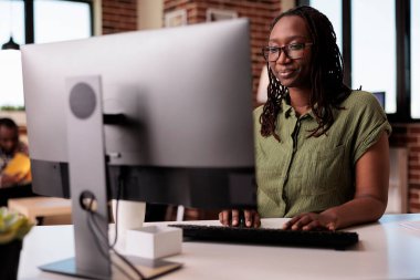 Kendine güvenen Afrikalı Amerikalı serbest yazar evden uzakta çalışırken bilgisayar ekranına bakıyor ve daktilo yazıyor. Ev arkadaşı dinlenirken ev oturma odasında bilgisayar kullanarak odaklanmış programcı kodlaması.