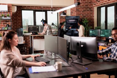 Programcılardan oluşan bir ekip, büyük ekranı programlamak için makine öğrenme uygulama kodunu analiz ediyor, şirket ofisinde duruyor. html betiği ile veritabanı sistemi üzerinde çalışan yazılım geliştiricileri