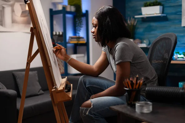 職場でイーゼルを鉛筆でスケッチする芸術家女性 アフリカ系アメリカ人の女性アーティストがキャンバスに手描きでドローイングを制作し 自宅のベッドルームでスケッチアトリエを作った — ストック写真
