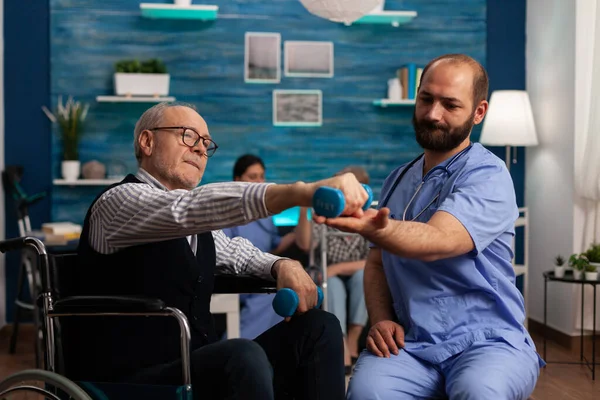 Fisioterapista Maschile Aiuta Uomo Anziano Una Sedia Rotelle Fare Esercizi — Foto Stock