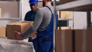 Depodaki paketlerdeki barkodları tarayan erkek yönetici, envanter çıkarmak için tarayıcı ve dijital tabletle çalışıyor. Endüstriyel bölümdeki stok lojistiğini kontrol eden genç bir çalışan.