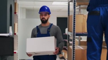 Çeşitli çalışanlardan oluşan bir ekip barkodları tarıyor, karton paketlerdeki ürünlere bakıyor. Ürünleri denetleyiciye getiren iki kişi, malları taramak için dijital tablet kullanıyor.