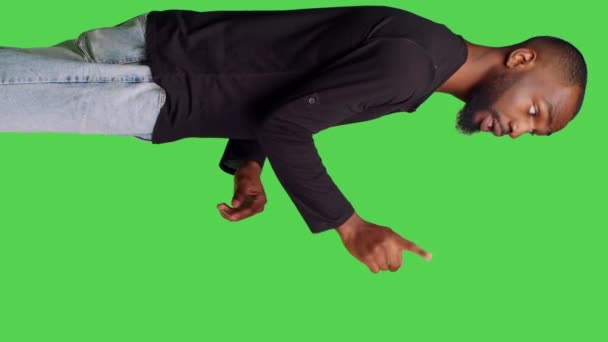 垂直ビデオ アフリカ系アメリカ人男性のプロフィールは 指でシンボルを示さず スタジオで拒絶と否定のジェスチャーをしています 緑の画面上に不承認と拒否のサインを表現する若い男性モデル — ストック動画