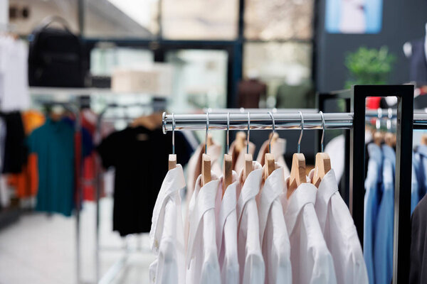 Shopping centre filled with new fashion collection, multiple racks with fashionable formal wear and trendy accessories. Empty clothing showroom with stylish shirts on hangers, small business concept.