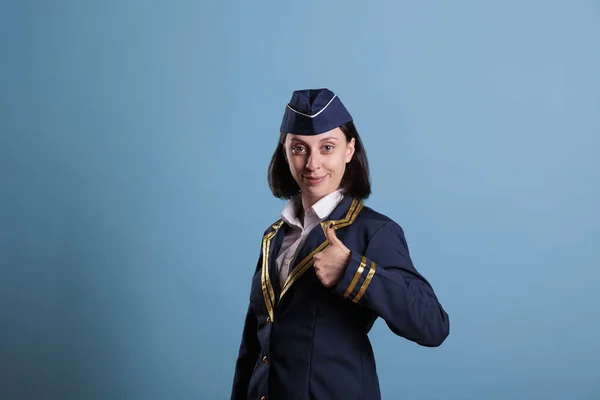 Portret Uśmiechniętej Stewardessy Wykonującej Gest Górę Stojącej Studio Niebieskim Tłem — Zdjęcie stockowe