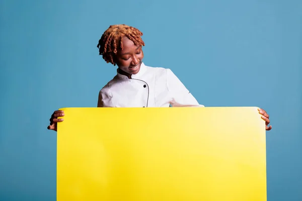 Cozinheiro Americano Africano Feliz Segurando Cartaz Amarelo Vazio Fundo Azul — Fotografia de Stock