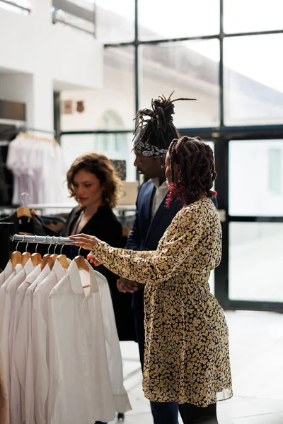 アフリカ系アメリカ人のカップルは 商業活動中にショールームの従業員に助けを求める流行のシャツを購入したい カジュアルウェアをお求めのお客様は モダンなブティックでファッショナブルな服を購入 — ストック写真