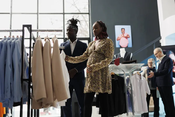 妊娠中の女性は ショールームで材料をチェックシャツを見て アフリカ系アメリカ人のカップル妊娠服の買い物 衣料品店で乳製品を購入するクライアント ファッションコンセプト — ストック写真