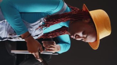 Dikey video: Modern model akıllı telefonu kontrol ediyor, tatil yerine gitmeden önce mesajlaşıyor. Genç bir kadın cep telefonuyla sosyal medyada geziniyor, seyahate çıkmaya hazırlanıyor. El bilgisayarı