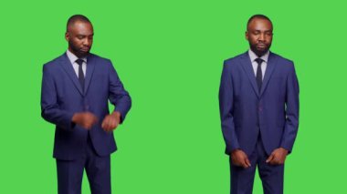 Afrika kökenli Amerikalı bir adam kol saatine bakıyor ve yeşil ekranda poz veriyor. Stüdyoda kendinden emin ve iyimser davranıyor. İzole edilmiş yeşil ekranda duran takım elbiseli genç yetişkin..