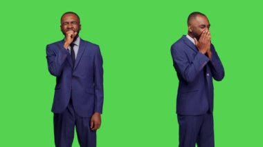 Genç yetişkin stüdyoda esniyor ve yorgun hissediyor uzun bir iş gününden sonra hayal kırıklığına uğruyor ve yoruluyor. İş adamı uykuya dalıyor ve bitkin düşüyor, yeşil perde arkaplanı.