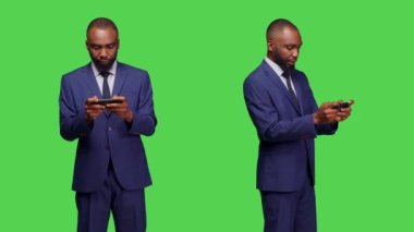 Kamerada mobil video oyunları oynayan kendine güvenen işadamı, online oyun ve rekabetle neşeli hissediyor. Takım elbiseli genç bir çalışan stüdyoda telefonda oyun yarışmasının keyfini çıkarıyor..