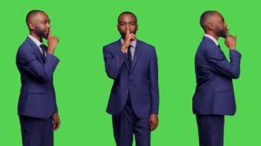 Afrikalı Amerikalı işadamı, stüdyoda sus işareti gösteriyor. Gizli kişi, sır ve mahremiyet için sessiz jest yapıyor. Erkek girişim çalışanı yeşil ekran üzerinde gizlilik uyarısı yapıyor.