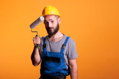 Uzman ressam paten ile tadilat üzerinde çalışıyor, duvarları boya ve boyayla boyuyor. İnşaat işçisi, stüdyo arkaplanını yenilemek için fırça tutuyor..