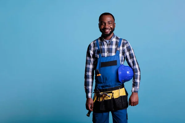 근로자는 안전띠와 모자를 작업복을 행복하게 지낸다 스튜디오에서 카메라를 아프리카 미국인 — 스톡 사진