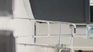 Dikey video: Klinik tesis resepsiyon masası hastane kayıt gişesine yerleştirilmiş yürüyüş çerçevesi, sağlık sigortası. Koltuklu sağlık merkezi ve randevu formları.