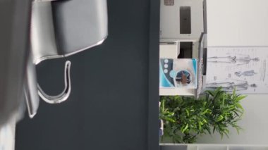 Dikey video: Tıp merkezindeki hastane bekleme odası, boş resepsiyon alanı, koltuklar ve sağlık broşürleri. Klinikte klinik randevuları ve hastalıklar için bekleme salonu