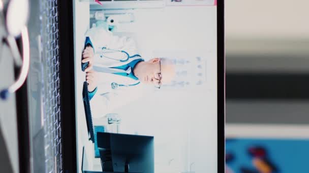 垂直视频 医学博士在办公桌上使用在线视频 笔记本电脑放在医院登记柜台上 专家参加远程保健会议 远程远程医疗医生会诊 接近了 — 图库视频影像